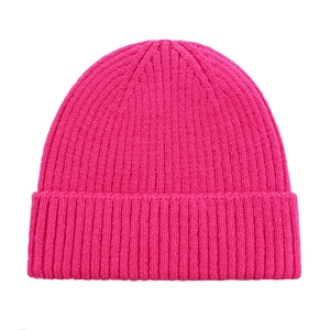 Macro view of bright fuchsia knitted beanie featuring thick ribbed texture and wide cuff