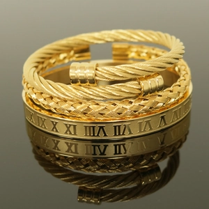 Macro shot of gold-plated crown bracelets set with roman numerals and braided rope texture
