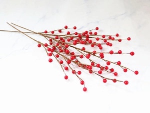Macro detail of artificial Christmas red holly berries branches on marble surface