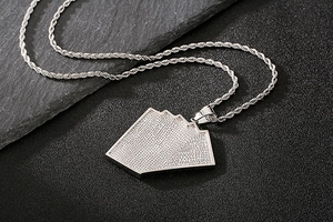 Macro shot of silver poker pendant with clear zircon inlay on textured stone background
