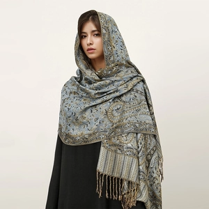 Detail of blue-grey paisley cashmere-like shawl with intricate golden floral weaving and fringes