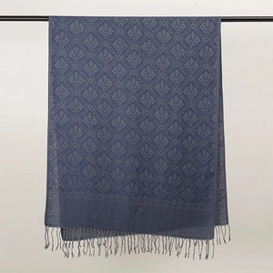 Dettaglio della sciarpa blu scuro con motivi damascati e rifinitura con frange eleganti