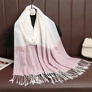 Dettaglio di sciarpa con motivo paisley rosa e nappe appesa su un abito scuro
