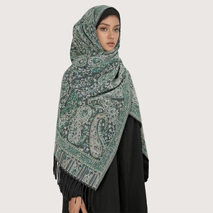 Close-up of green core-spun yarn scarf with paisley patterns and decorative fringe details
