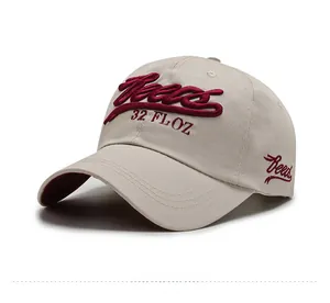 Detailed embroidery of bold red artistic font on beige cotton baseball cap with curved brim