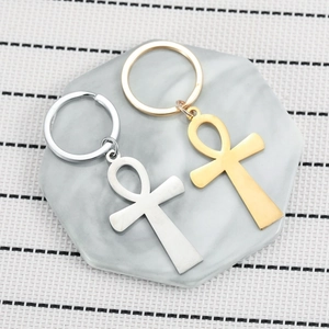 Golden and silver stainless steel Ankh keychains on marble coaster background