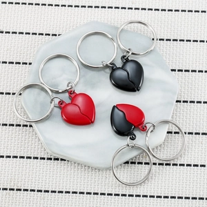 Magnetic heart couple keychains in black and red on a white ceramic tray