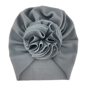 Detail of grey baby headband featuring waffle knit texture and a large 3D fabric flower