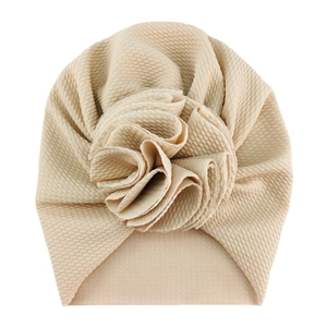 Detail of baby turban hat showing waffle knit fabric texture and 3D flower in beige