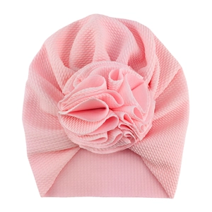 Close-up of pink waffle knit baby turban hat with a large decorative 3D flower detail