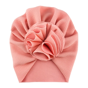 Detailed close-up of pink textured knit baby turban hat with oversized 3D flower