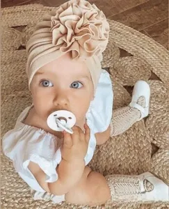 Detailed texture of baby sunflower turban hat in beige knit with large floral knot