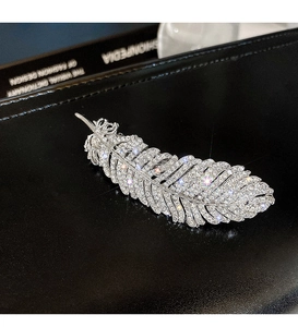 Close-up of a silver feather hair clip with rhinestones on a black leather background