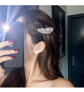 Detail of a sparkling rhinestone feather hair clip worn on the side of the head