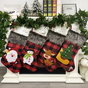 Red and black buffalo plaid Christmas stockings with 3D applique hanging on fireplace