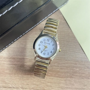 Top view of a gold-toned quartz watch with stretch band and white dial on wood background