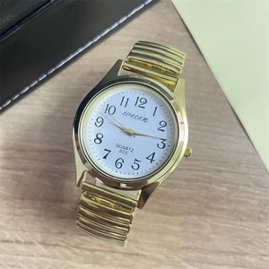 Macro shot of quartz watch dial with large numerals on a wooden surface backdrop