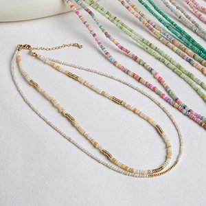 Double-layered beaded necklace with white pearls and gold spiral metal accents on white base