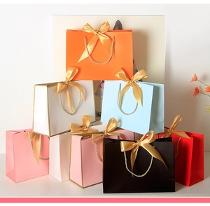 Close-up of premium paper gift bags with gold ribbon bows and elegant gilded edges
