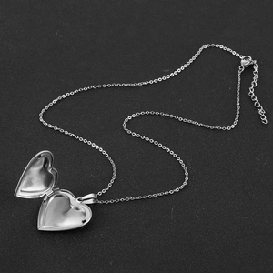 Close-up of heart locket necklace showing silver extension chain and lobster clasp