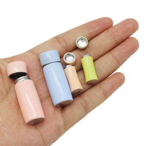 Miniature dollhouse vacuum flasks in pastel colors shown on hand for scale