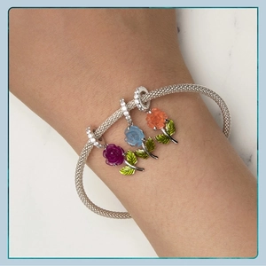 Macro detail of S925 silver mesh bracelet with colorful rose charms on a female wrist