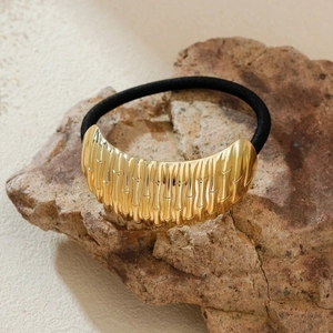 Elegant gold metal bamboo joint hair tie on a natural rock prop with a beige background