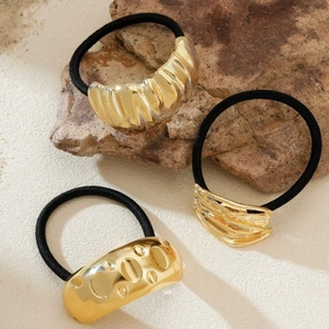 Three minimalist gold metallic hair ties with wave and hammered textures on elastic bands