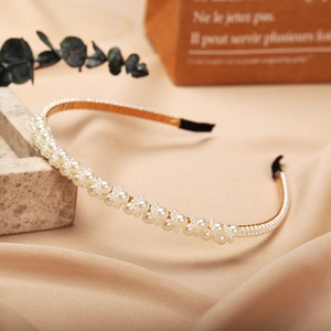 Elegant vintage gold metal headband with white faux pearls on a silk background