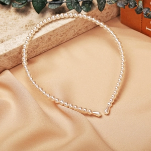 Close-up of elegant cream white pearl headband on champagne satin fabric
