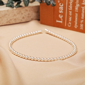 Detailed close-up of cream white faux pearl headband on vintage silk fabric