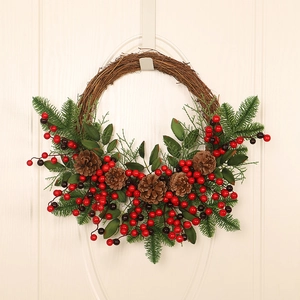 Christmas wreath with pine cones and red berries hanging on a white door