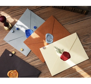 Detailed view of linen texture envelopes with decorative wax seals on dark wood