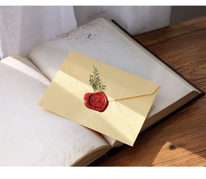 Close-up of vintage hemp texture envelope with wax seal on antique book and wooden table