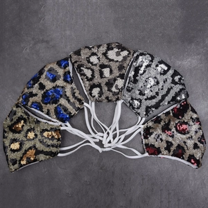Close-up of five colorful leopard sequin masks neatly arranged on a grey rock background