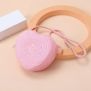Detailed view of pink heart-shaped straw bag with intricate woven texture on warm background