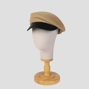 Chic khaki woven baker boy hat with black leather brim on a mannequin head
