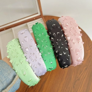 Handheld display of colorful hollow heart sponge headbands in pink, green, and purple