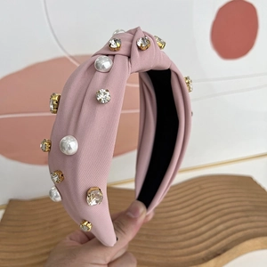 Close-up of pink fabric headband featuring white pearls and sparkling rhinestones