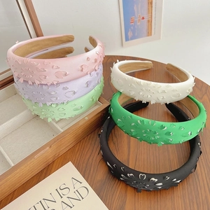 Pink and multicolored hollow floral sponge headbands displayed on a wooden jewelry box