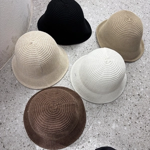 Flat lay of knit bucket hats in black, beige, cream, dark brown, and khaki colors