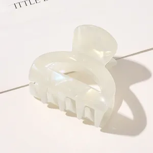 Detail of elegant butterfly acetate hair claw clip with pearlescent finish in warm white
