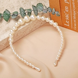 Detailed view of layered faux pearls on an elegant headband with a soft silk background