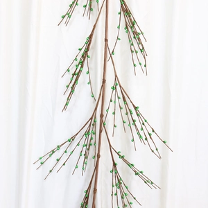Tige de baies vertes artificielles pour décoration de Noël sur tissu blanc drapé