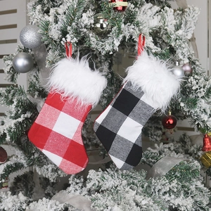 Checkered Christmas stockings with plush trim hanging on a snowy festive holiday tree