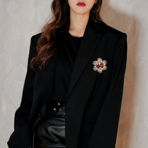 Vintage floral starburst brooch with red gemstone and crystals on a black suit jacket