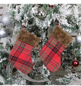 Close-up of red and green plaid Christmas stockings with faux fur on a festive tree