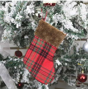 Close-up of a red and green plaid Christmas stocking with faux fur hanging on a tree