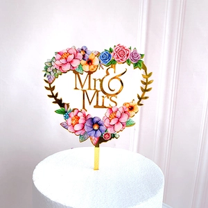 Golden acrylic heart cake topper with Mr & Mrs text and colorful floral patterns