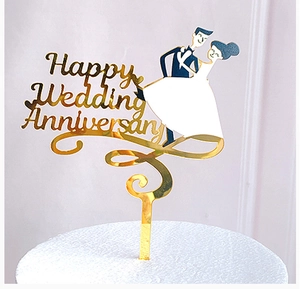 Close-up of golden mirror acrylic cake topper with Happy Wedding Anniversary text